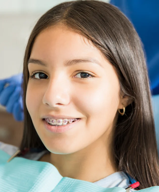 Adolescente souriante avec appareil dentaire métallique au fauteuil