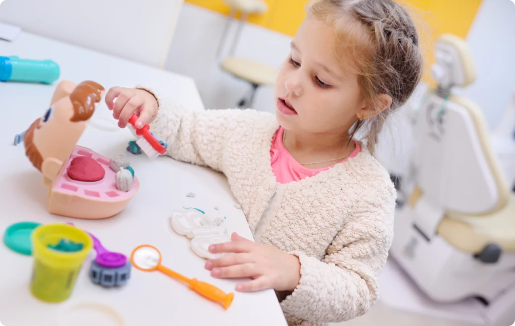 Petite fille jouant avec un modèle dentaire et des instruments
