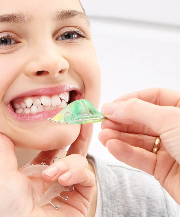Fillette souriante et plaque palatine verte
