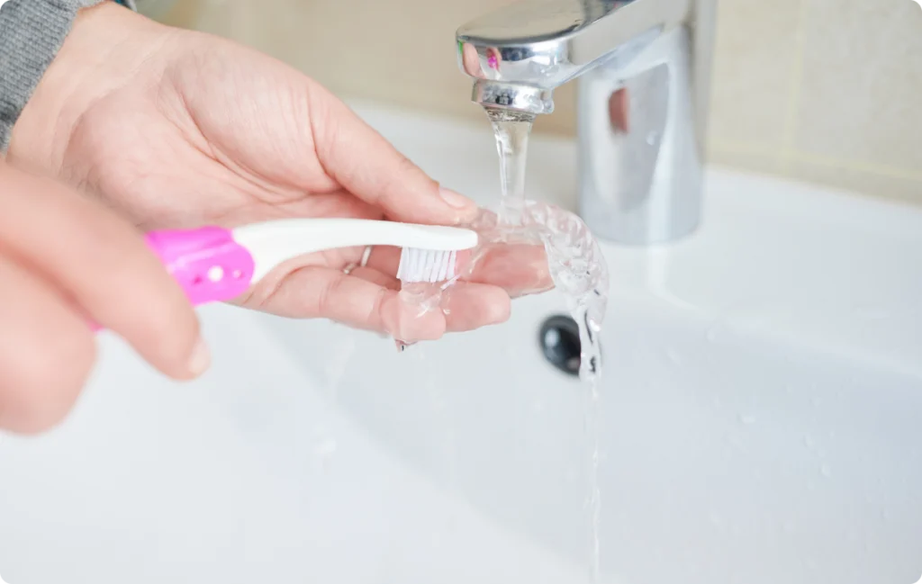 Nettoyage d’un aligneur à la brosse sous l’eau du robinet
